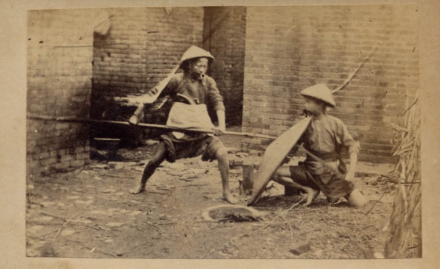 A third picture from the same series.  Note the long thin blade being held behind the rattan shield by the kneeling individual.  source http://www.swordsantiqueweapons.com.